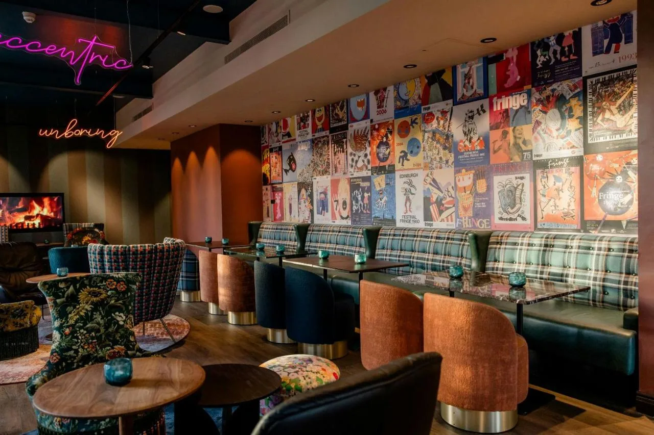 a restaurant with a bar with chairs and tables at Motel One Edinburgh-Princes in Edinburgh